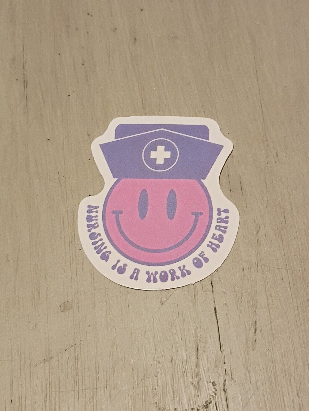 10/$10 Sticker Decal - Nursing Is A Work Of Heart - Pink Smiley Face, Purple Hat